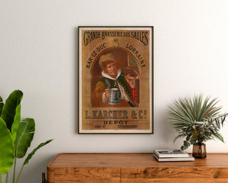 Manifesto pubblicitario vintage Brasserie des Saules, Bar-le-Duc, incorniciato sopra una credenza in legno, tra delle piante.