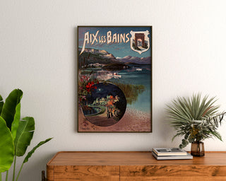Vintage-Plakat «Aix-les-Bains, fête de nuit», eingerahmt über einer Holzkommode, zwischen Pflanzen.