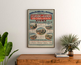 Vintage-Plakat Auvergne, Ausflüge PLM, gerahmt über einer Holzkommode, zwischen Pflanzen.