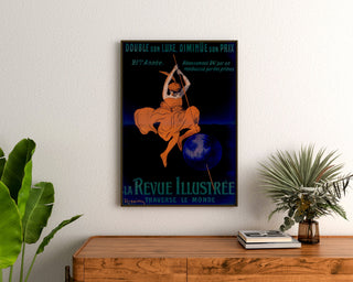 Vintage-Poster La Revue illustrée, gerahmt über einer Holzkommode zwischen Pflanzen.