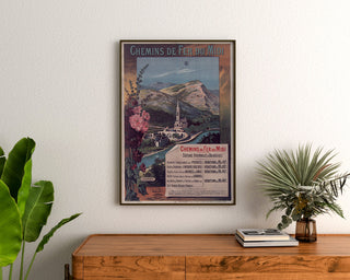 Manifesto vintage Lourdes, località balneari, incorniciato sopra una cassettiera in legno, tra piante.