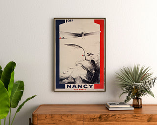 Manifesto vintage Nancy, meeting d’aviation, incorniciato sopra una credenza in legno, tra delle piante.