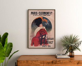 Vintage-Plakat Paris-Clermont, Wintersaison, gerahmt über einer Holzkommode, zwischen Pflanzen.